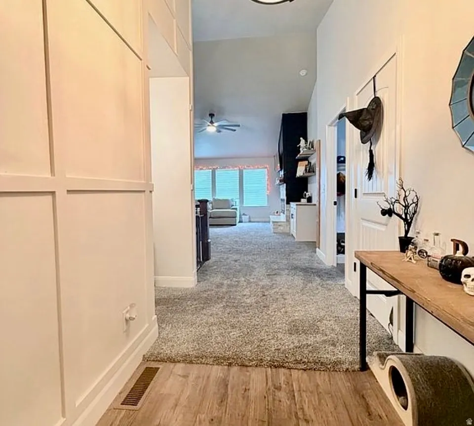Corridor with light wood-style flooring and vaulted ceiling