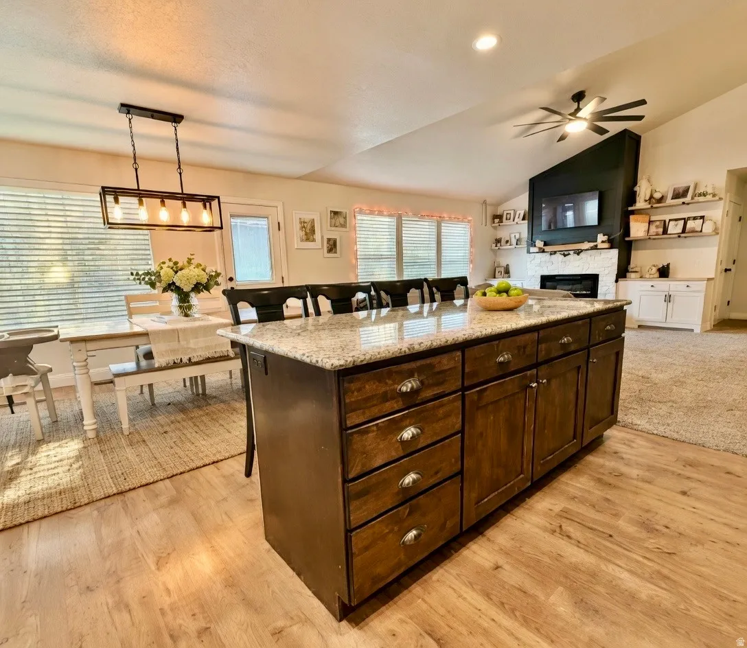 Kitchen with a breakfast bar, dark wood finish cabinetry, a kitchen island, decorative light fixtures, and lofted ceiling