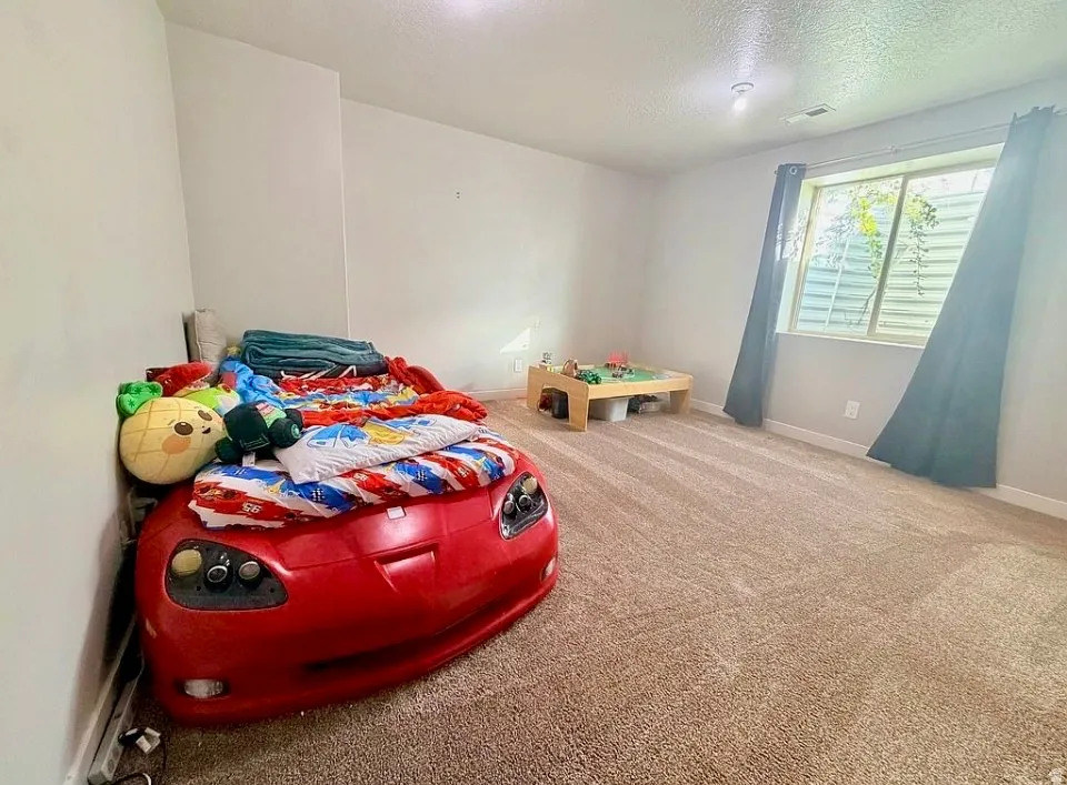Bedroom featuring light colored carpet and a textured ceiling