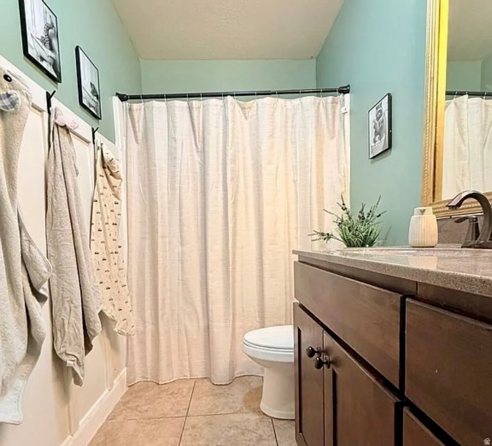 Bathroom featuring vanity, curtained shower, light tile patterned flooring, and a textured ceiling