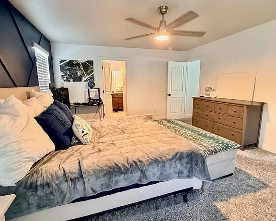 Carpeted bedroom featuring ensuite bathroom and a ceiling fan