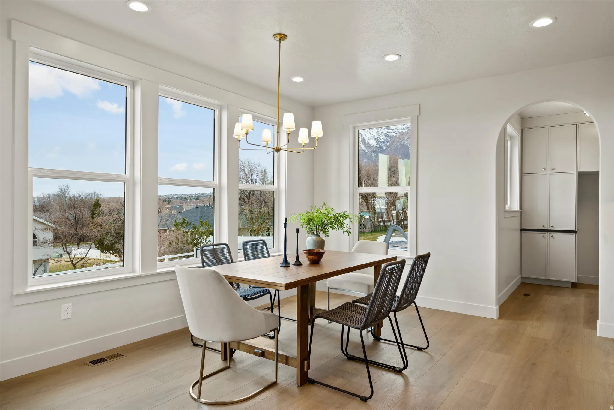 Dining space with arched walkways, light wood finished floors, and a chandelier