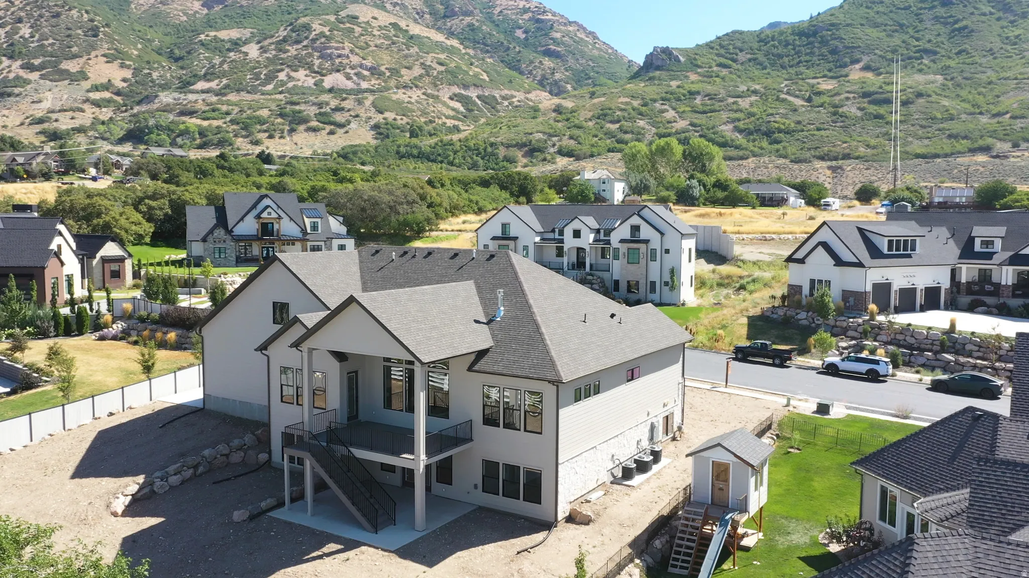 Modern two-story residence with a covered balcony, lower-level patio, and exterior stairs