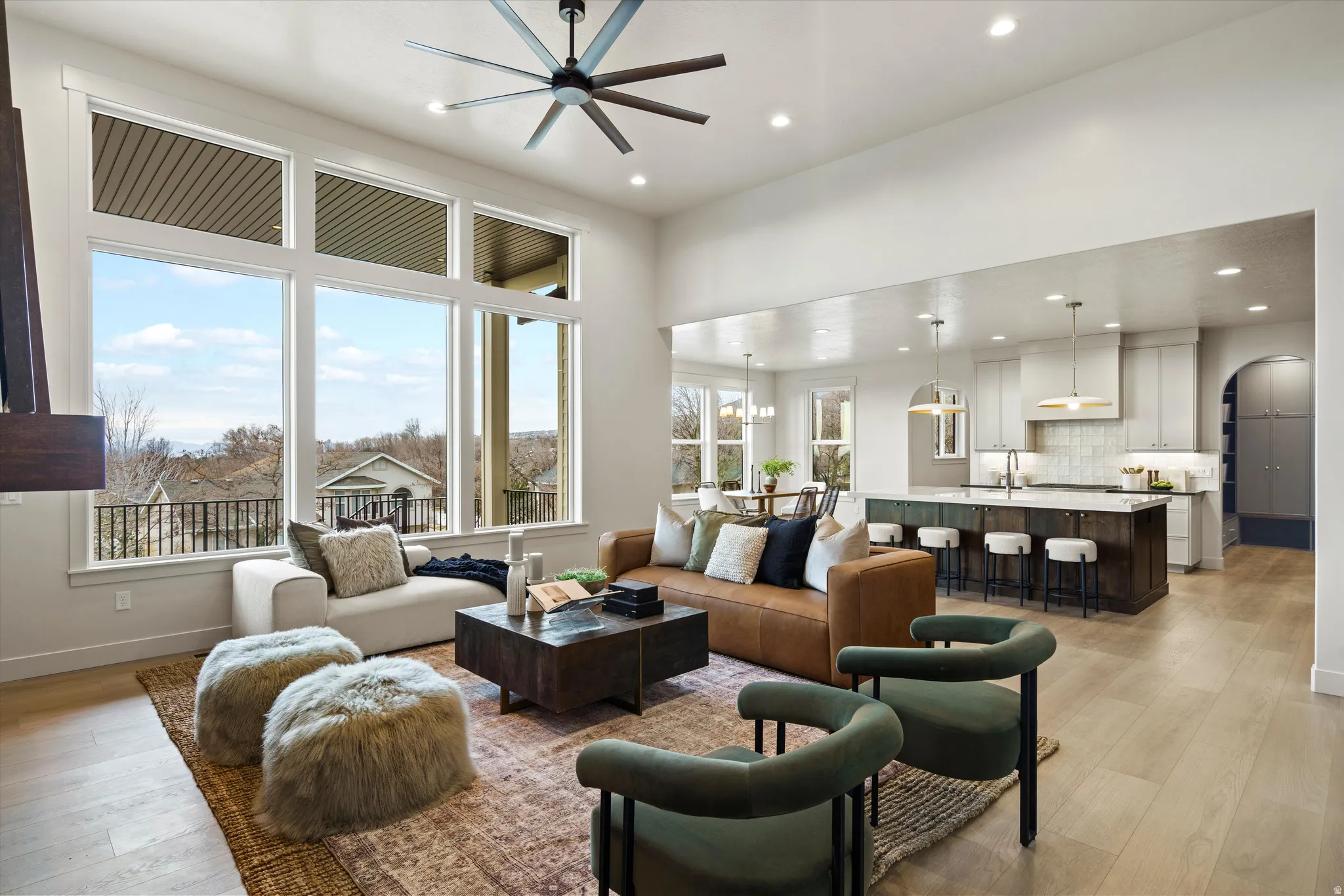 Living room with light wood-style floors, arched walkways, ceiling fan, and recessed lighting