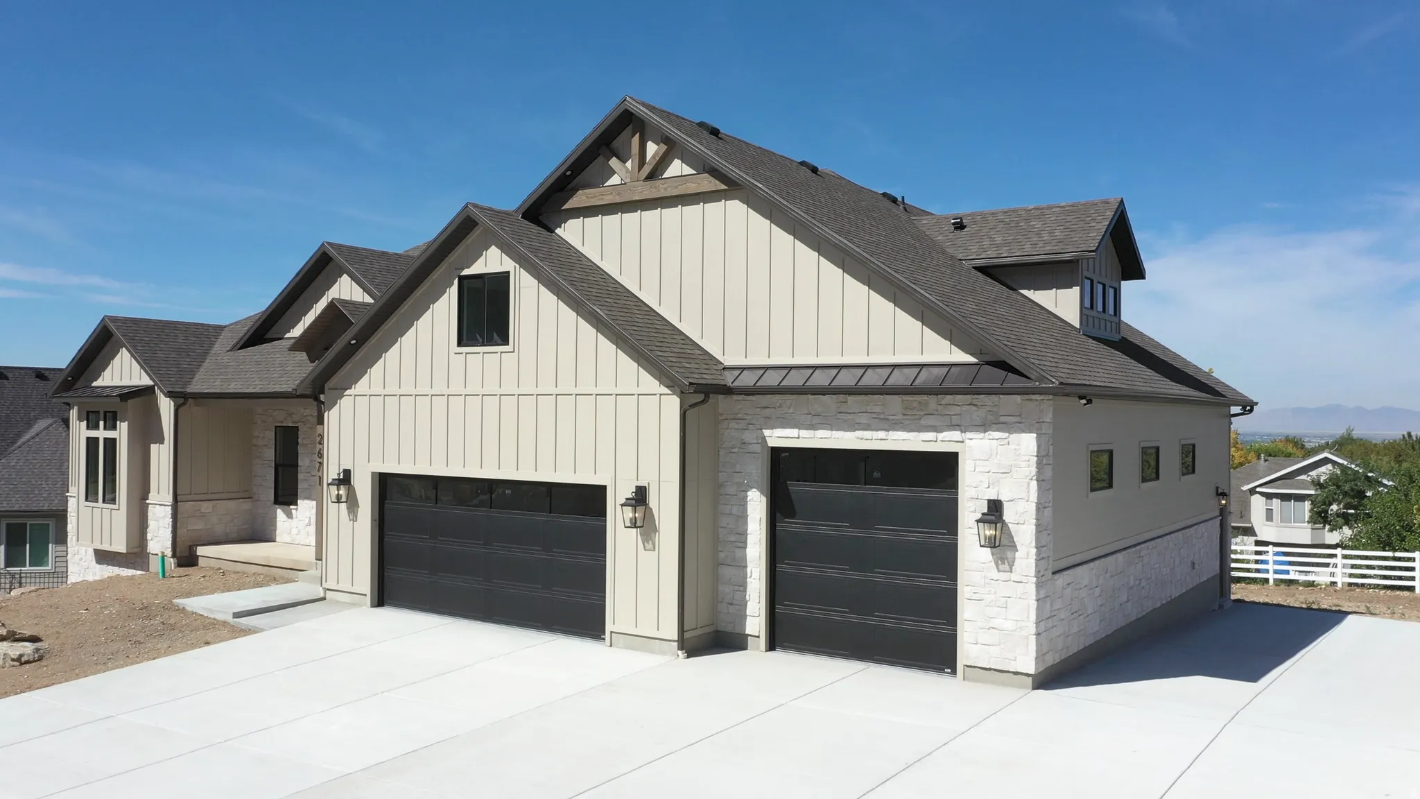 Modern farmhouse architecture with vertical siding, stone accents, dark garage doors, and a durable asphalt shingle roof