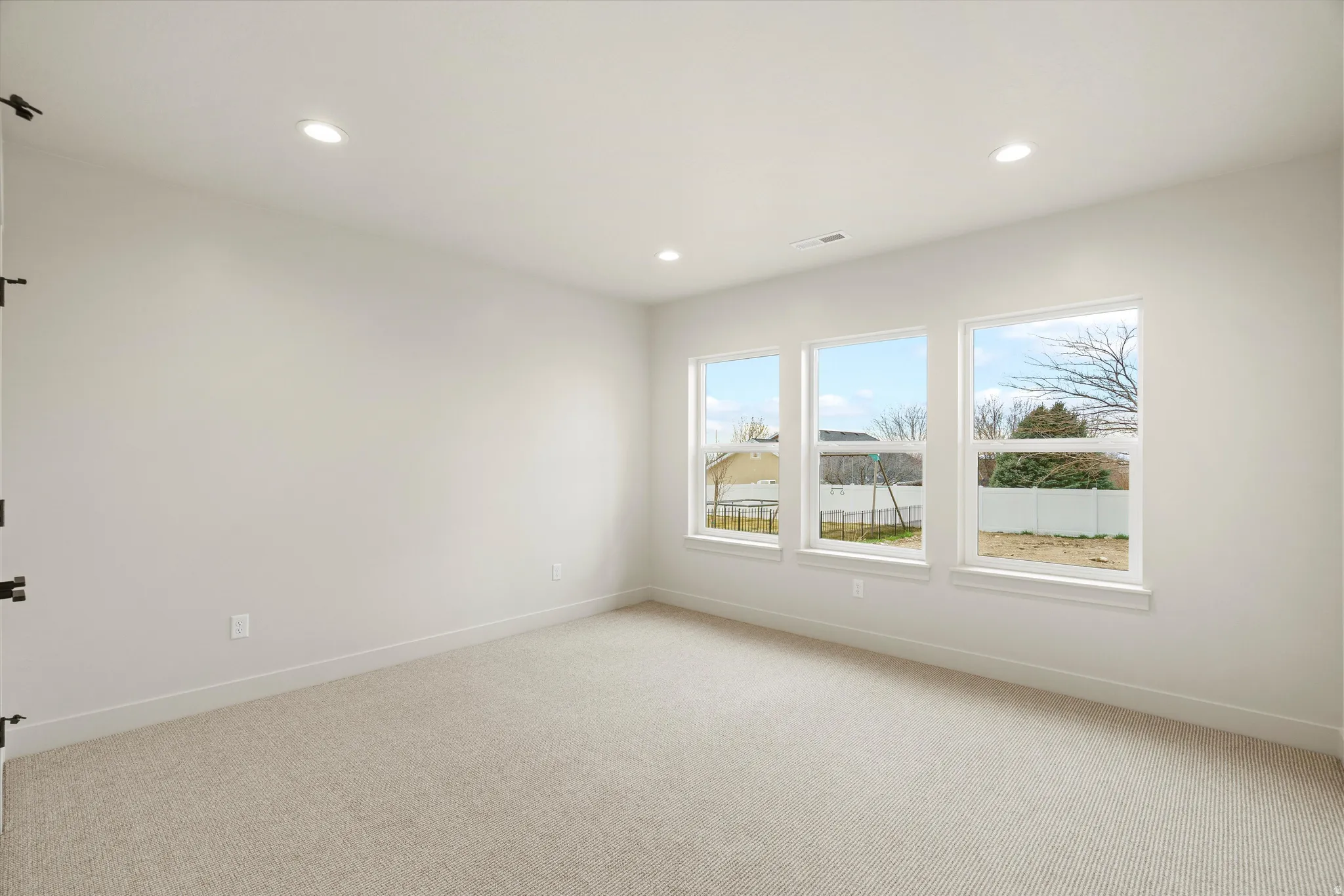 Empty room with light colored carpet and recessed lighting