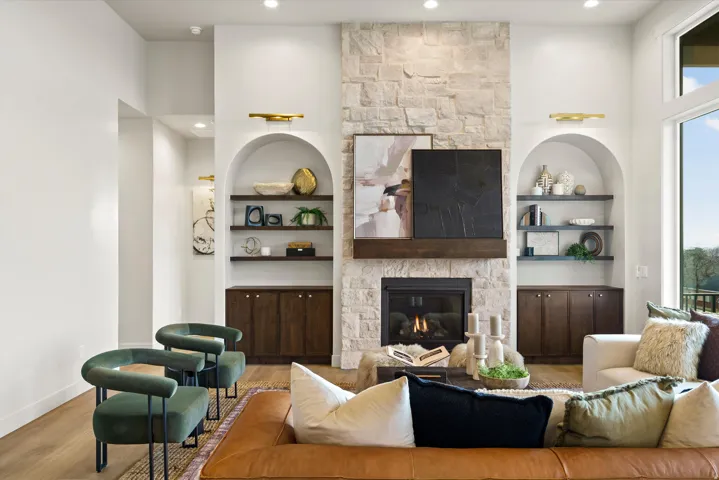 Living room with a fireplace, wood finished floors, recessed lighting, and a high ceiling