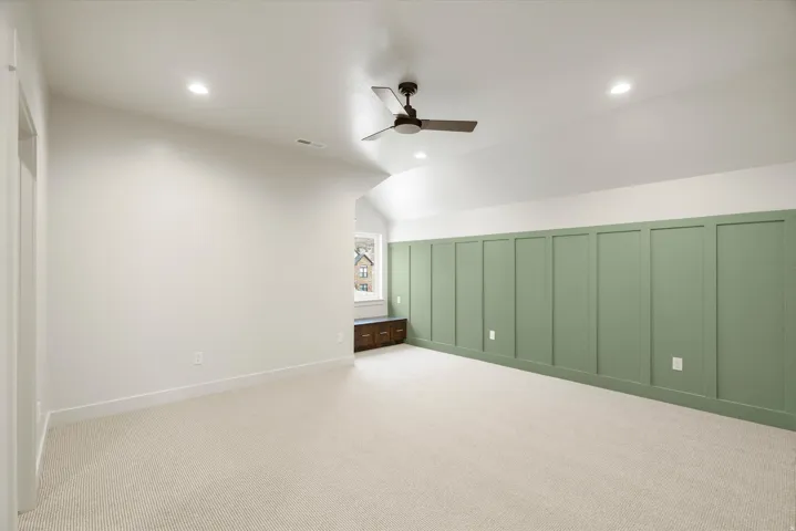 Bonus room featuring a decorative wall, lofted ceiling, a ceiling fan, and light carpet