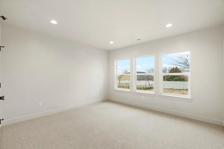 Empty room with light colored carpet and recessed lighting