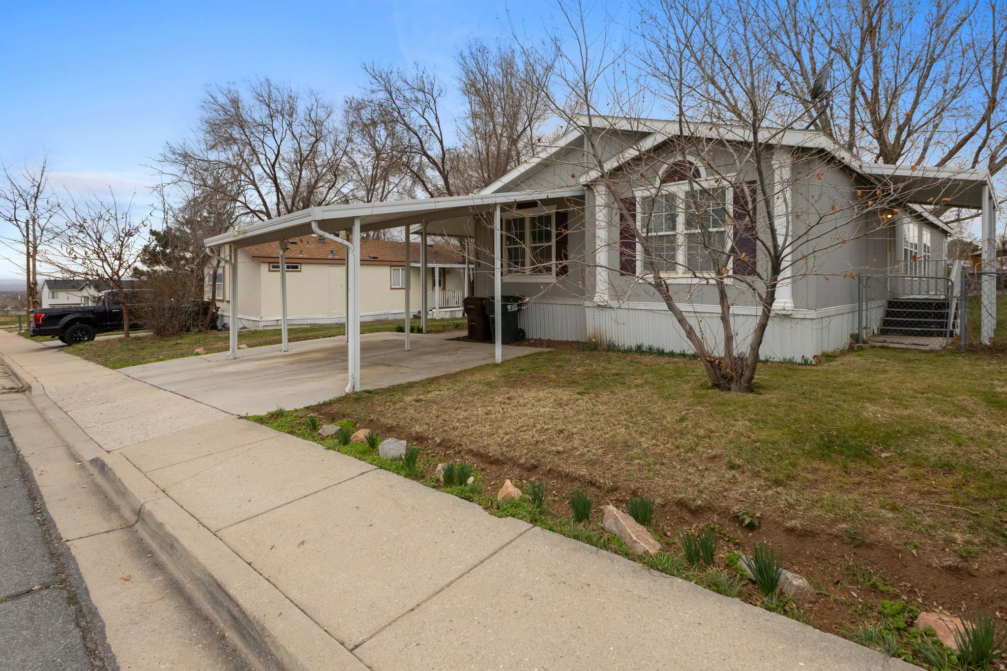 View of front facade with a front yard, a carport, and driveway