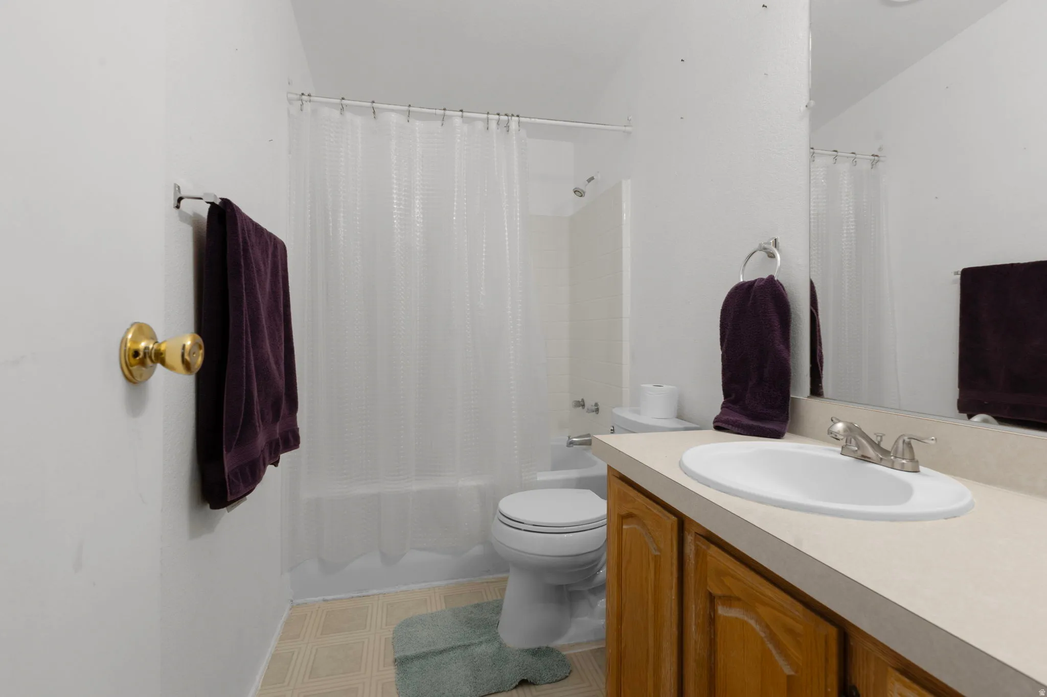 Bathroom featuring vanity, shower / bath combo, and light floors