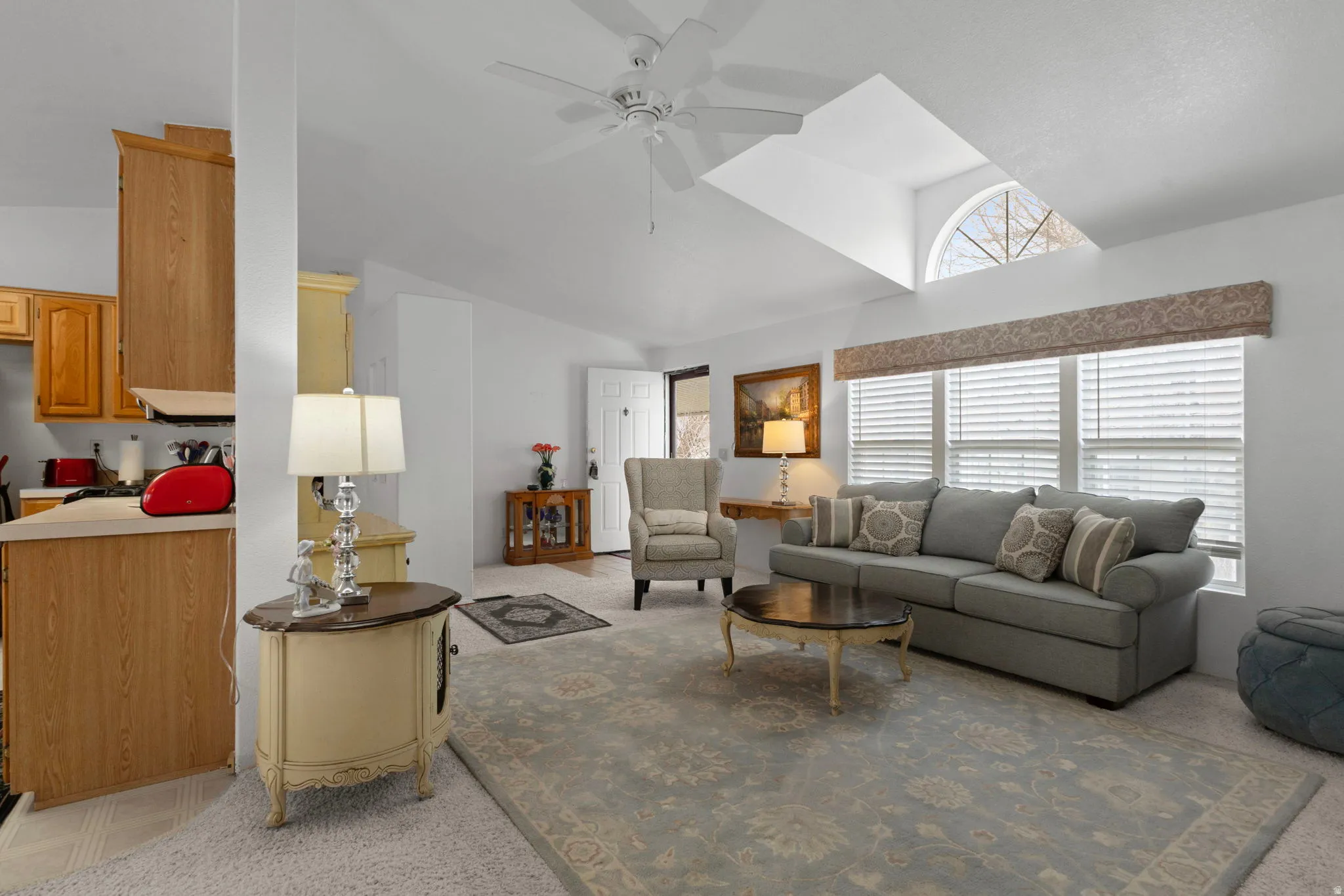 Living area with ceiling fan, vaulted ceiling, and light colored carpet