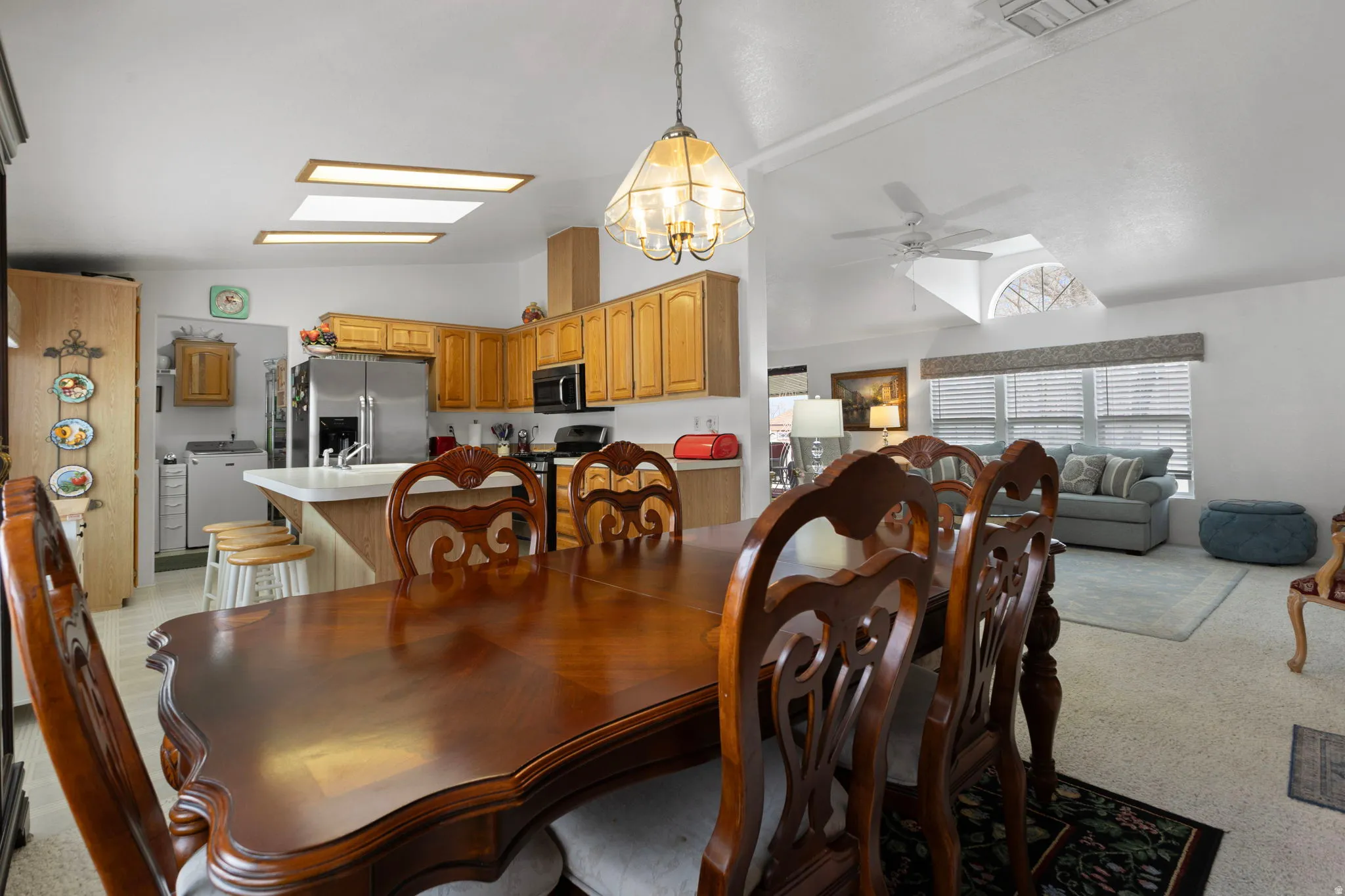 Dining space featuring lofted ceiling, ceiling fan, a skylight, washer / clothes dryer, and a chandelier
