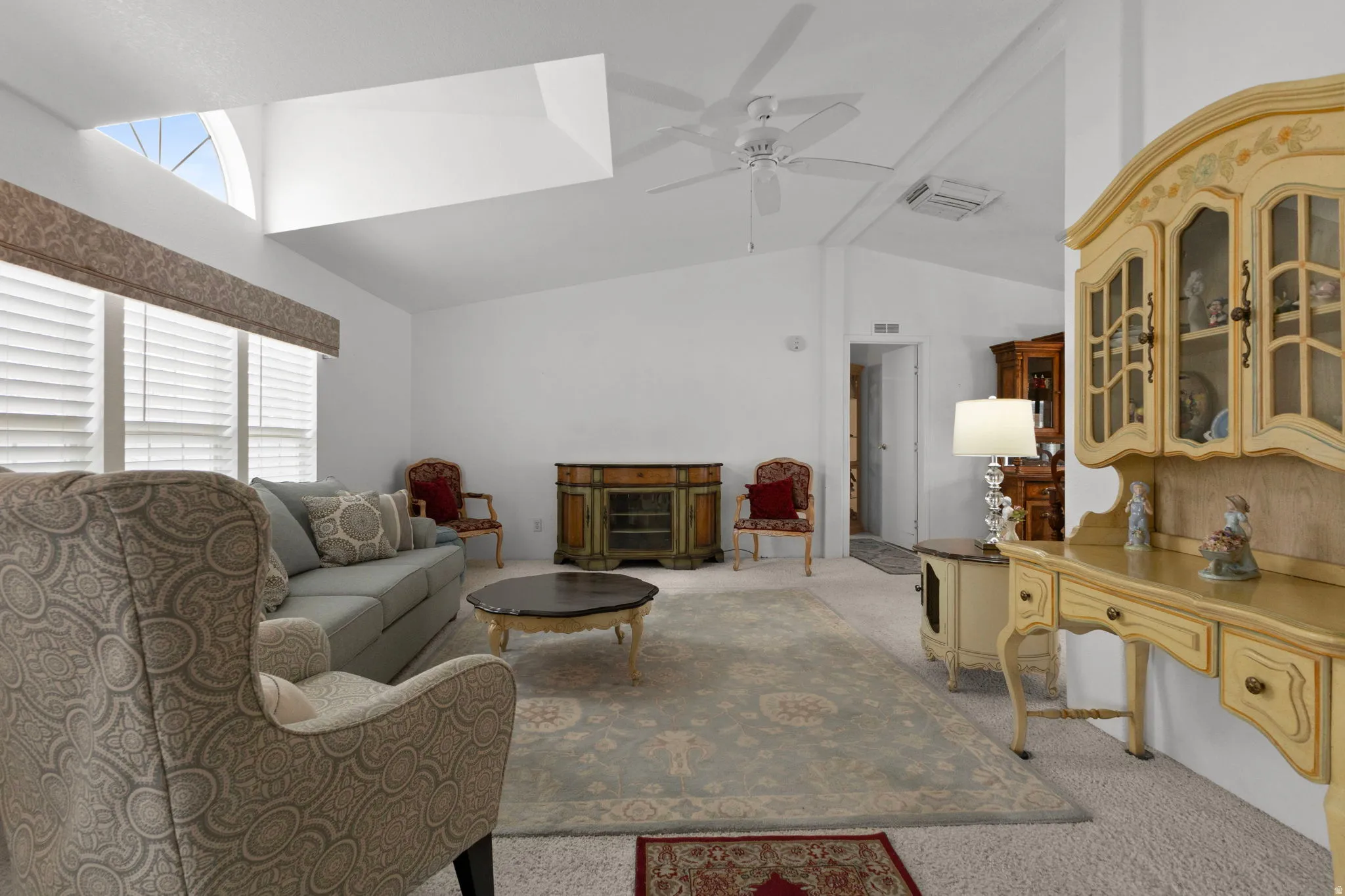 Living area featuring light colored carpet, vaulted ceiling, and ceiling fan