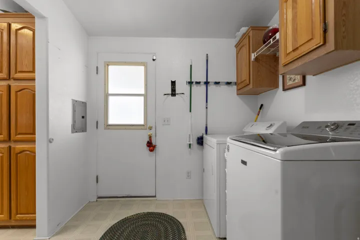 Laundry room featuring cabinet space, light floors, independent washer and dryer, and electric panel