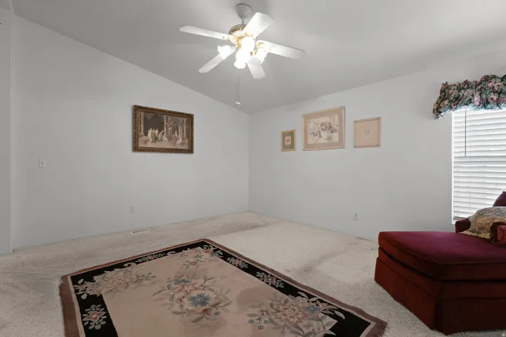 Sitting room featuring ceiling fan, carpet, and lofted ceiling