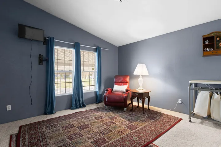 Living area with vaulted ceiling and carpet flooring