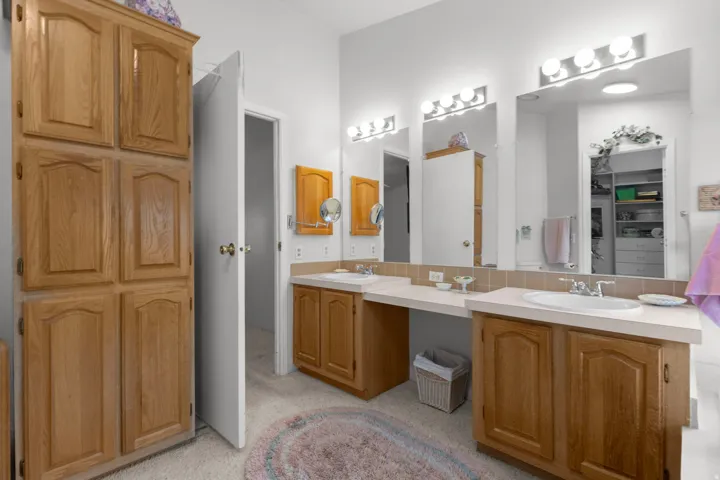 Full bath featuring double vanity, decorative backsplash, and a spacious closet