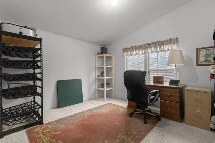 Office area with lofted ceiling and light colored carpet