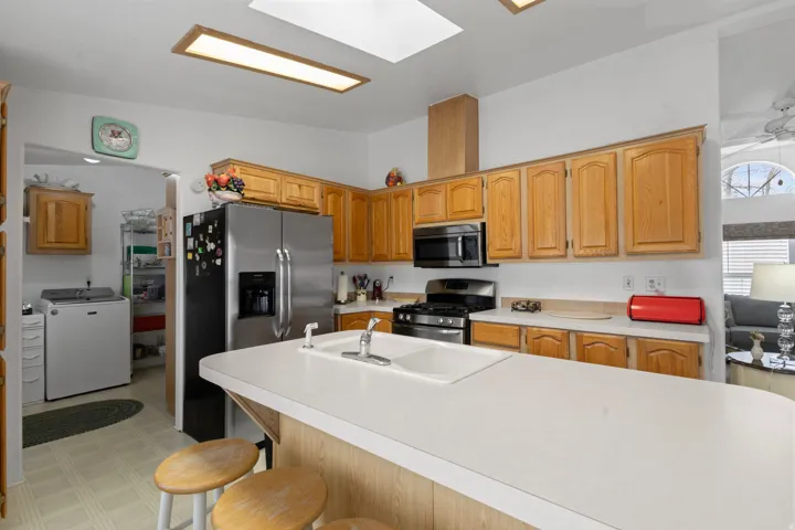 Kitchen featuring light countertops, light floors, washer / clothes dryer, stainless steel appliances, and a kitchen breakfast bar
