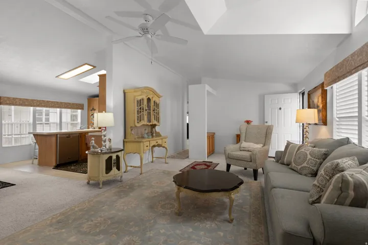 Living room featuring light carpet, vaulted ceiling, and a ceiling fan