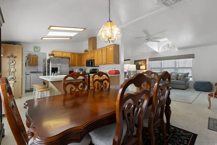 Dining space featuring lofted ceiling, ceiling fan, a skylight, washer / clothes dryer, and a chandelier
