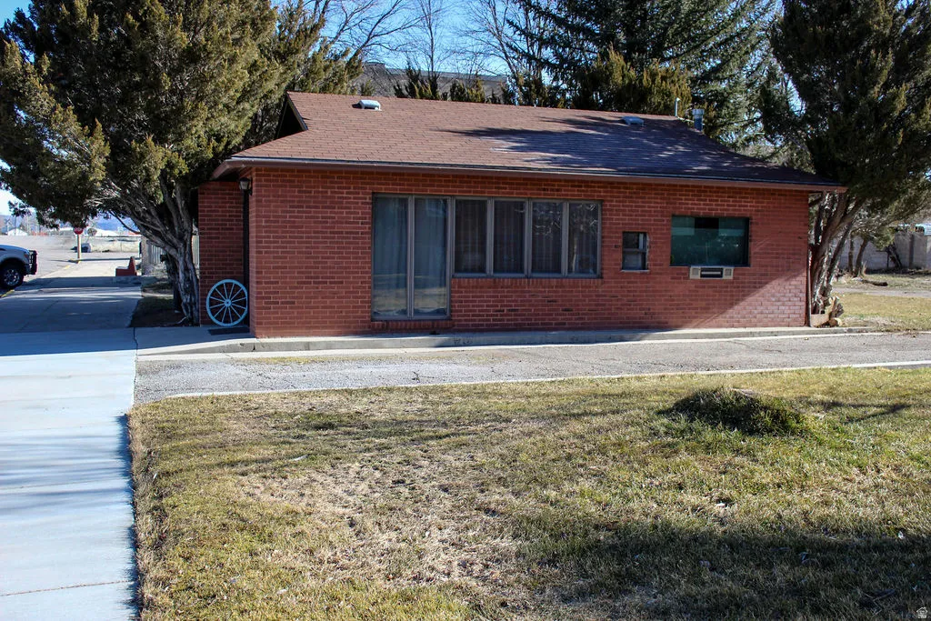 Rear view of house featuring brick siding, a yard, and roof with shingles