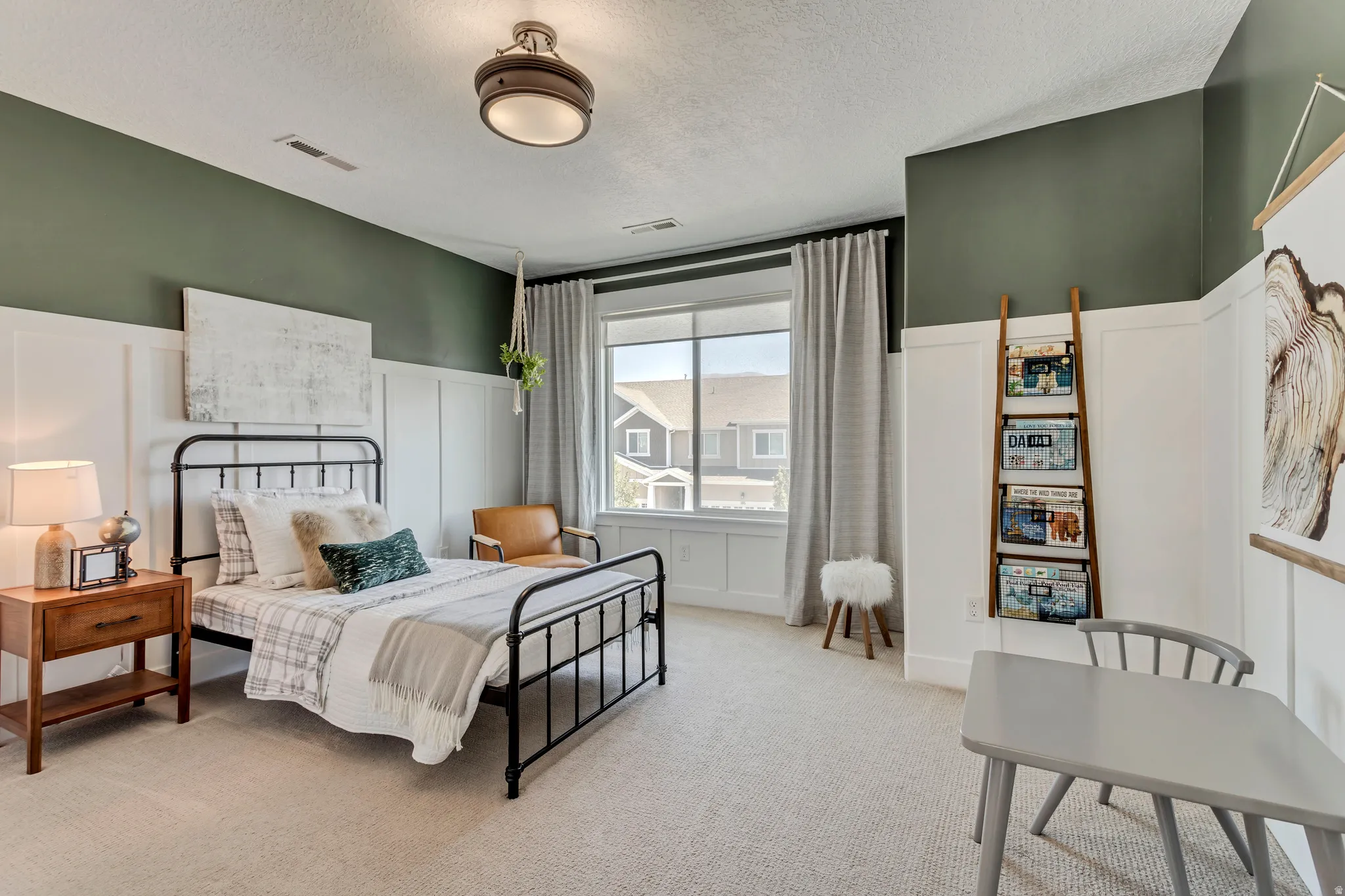 Bedroom with a decorative wall, a wainscoted wall, and light colored carpet