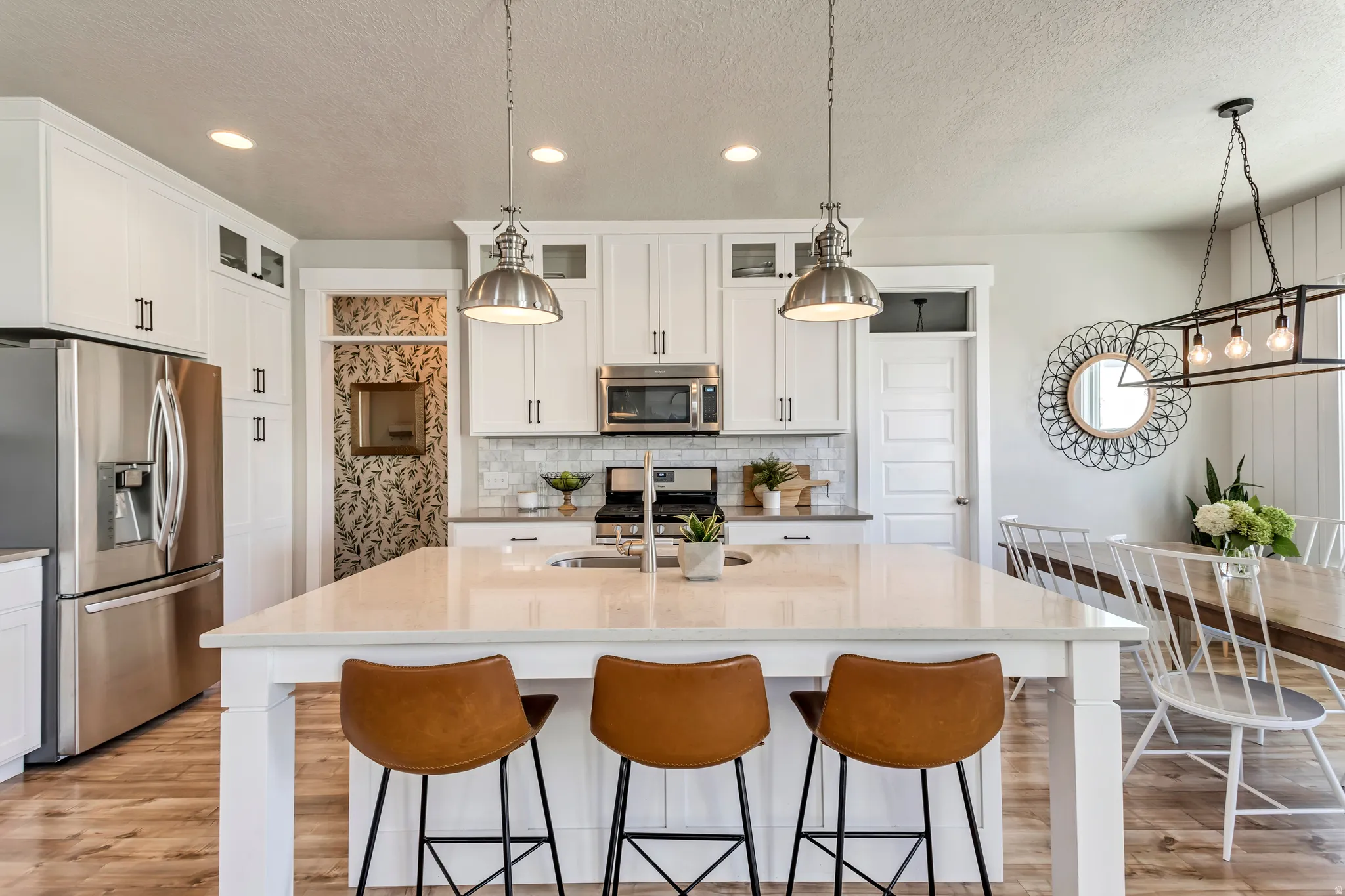 Kitchen with stainless steel appliances, white cabinetry, light wood-style flooring, and light stone counters