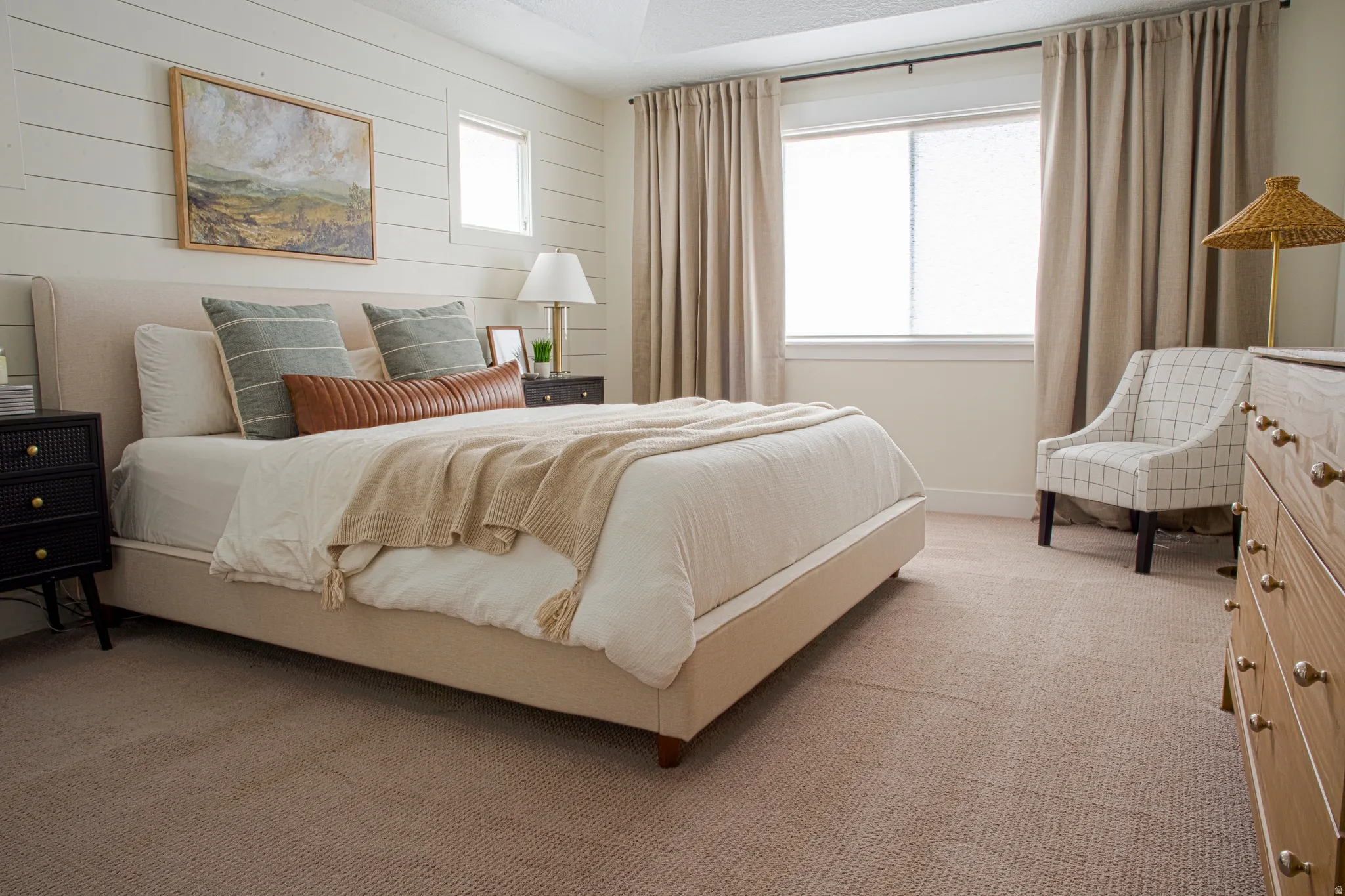 Primary bedroom with light colored carpet and paneled