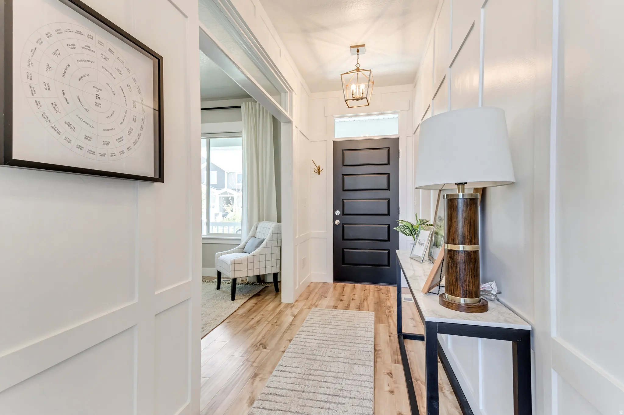 Foyer with light wood finished floors, hanging lights, and a decorative wall