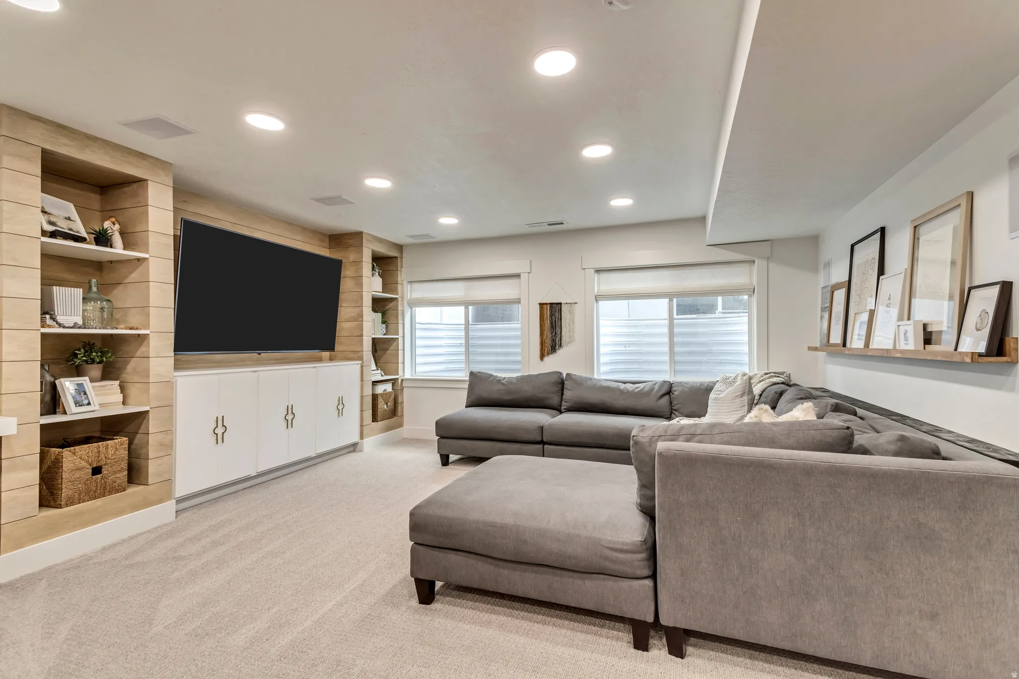 Living area with light colored carpet, built-in entertainment center, and recessed lighting