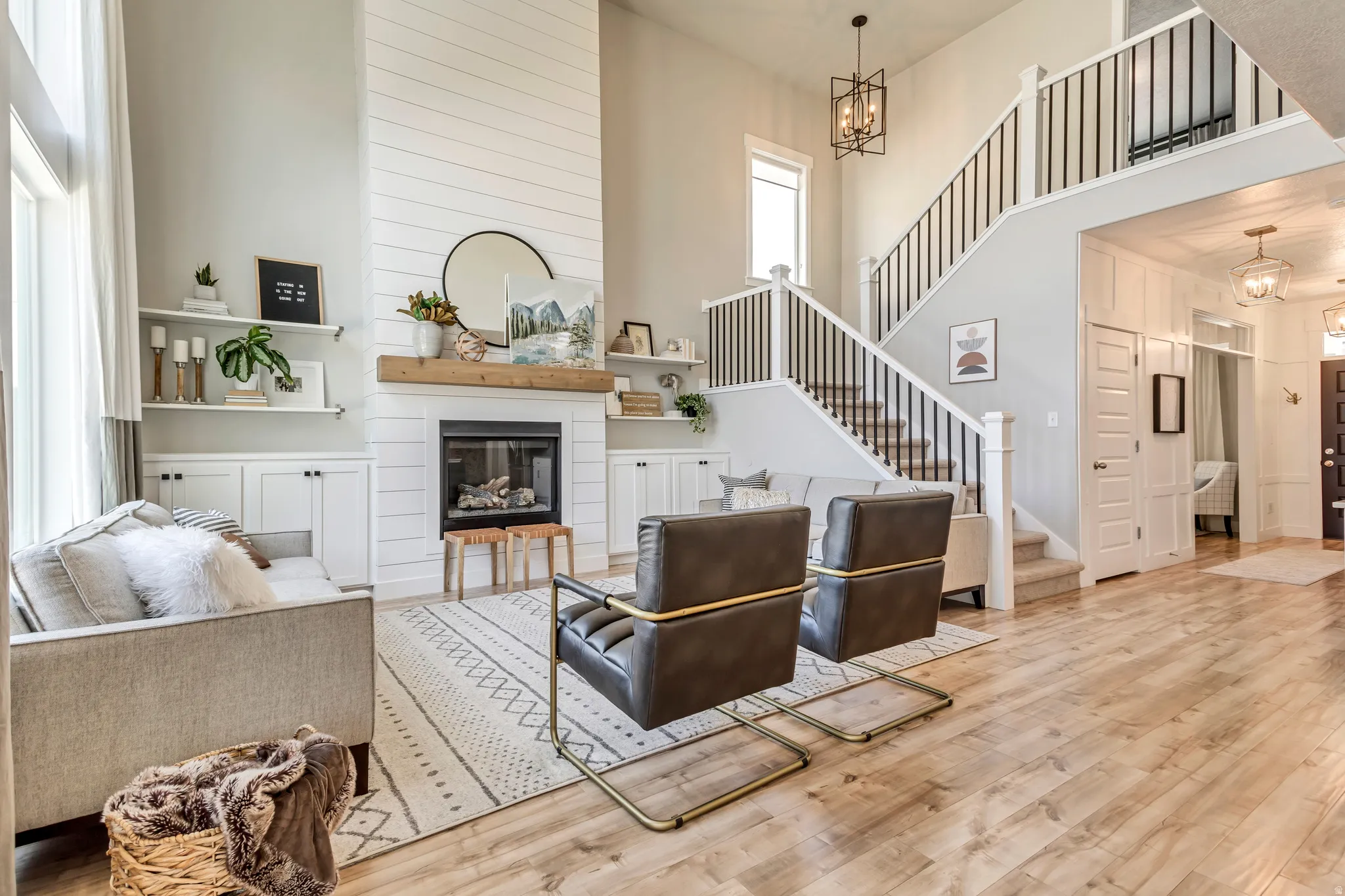Living area featuring a high ceiling, suspended lighting, wood finished floors, and a large fireplace