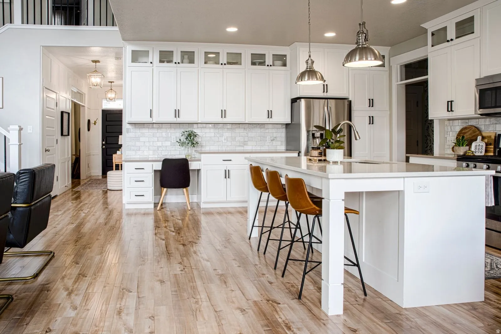 Kitchen featuring a breakfast bar, glass insert cabinets, stainless steel appliances, hanging light fixtures, and decorative backsplash