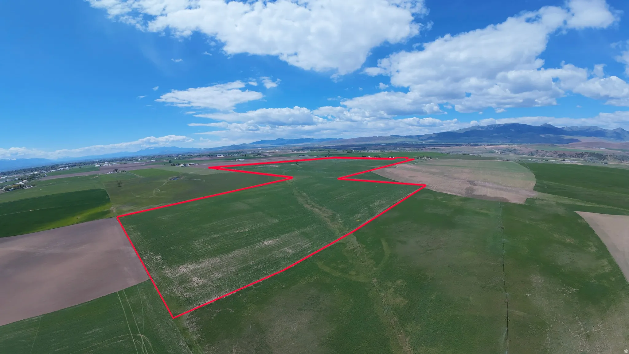 Expansive green fields outlined, surrounded by additional fields, and distant mountains