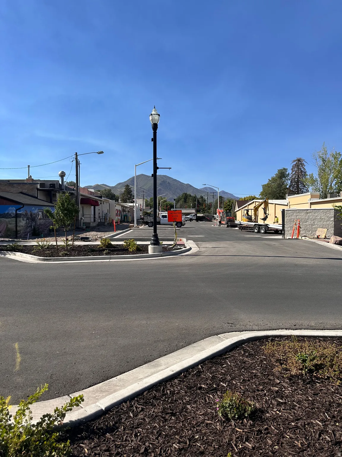View of asphalt street featuring curbs, street lights, a mountain view, and sidewalks