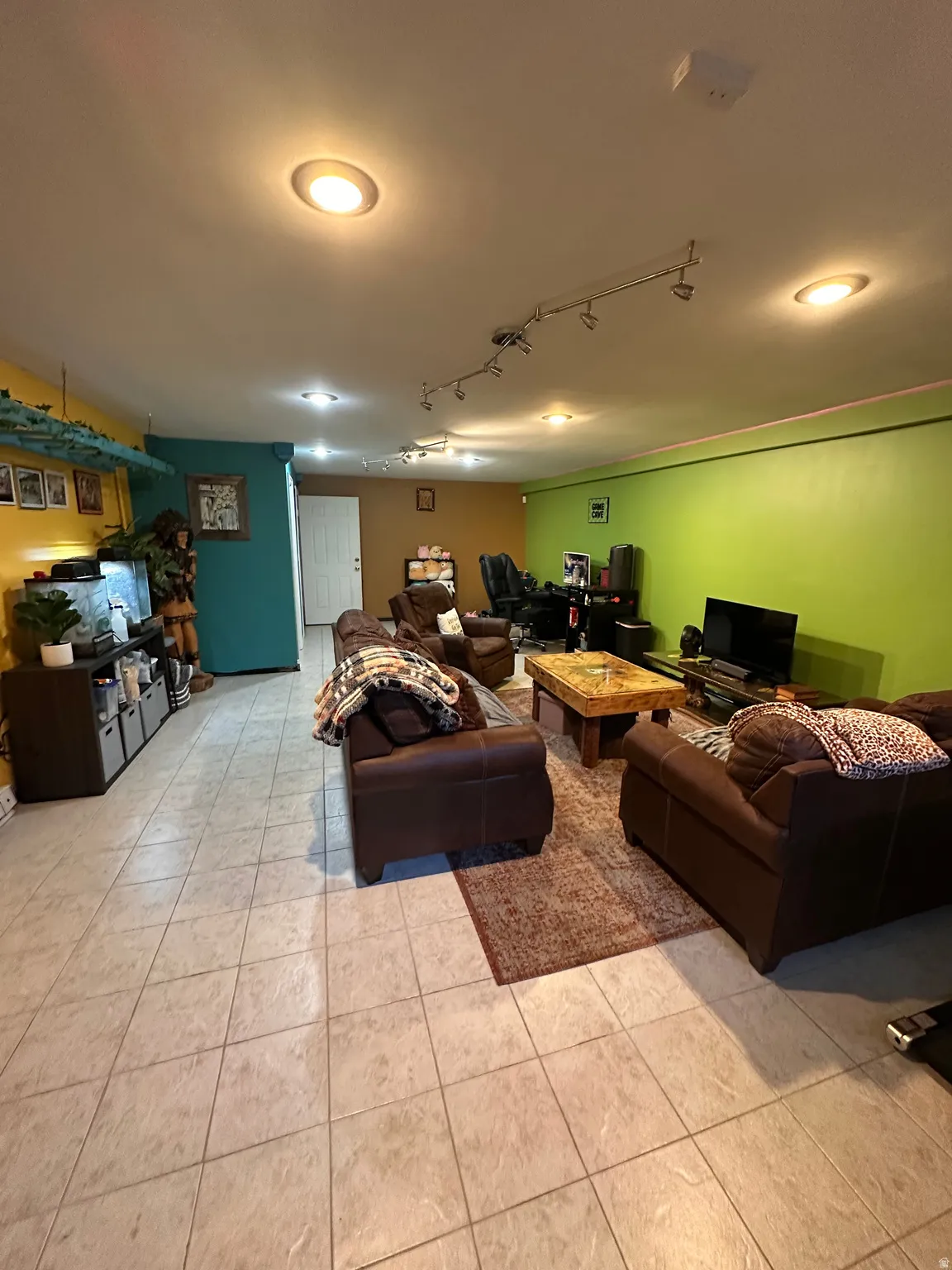 Living area featuring track lighting and light tile patterned flooring