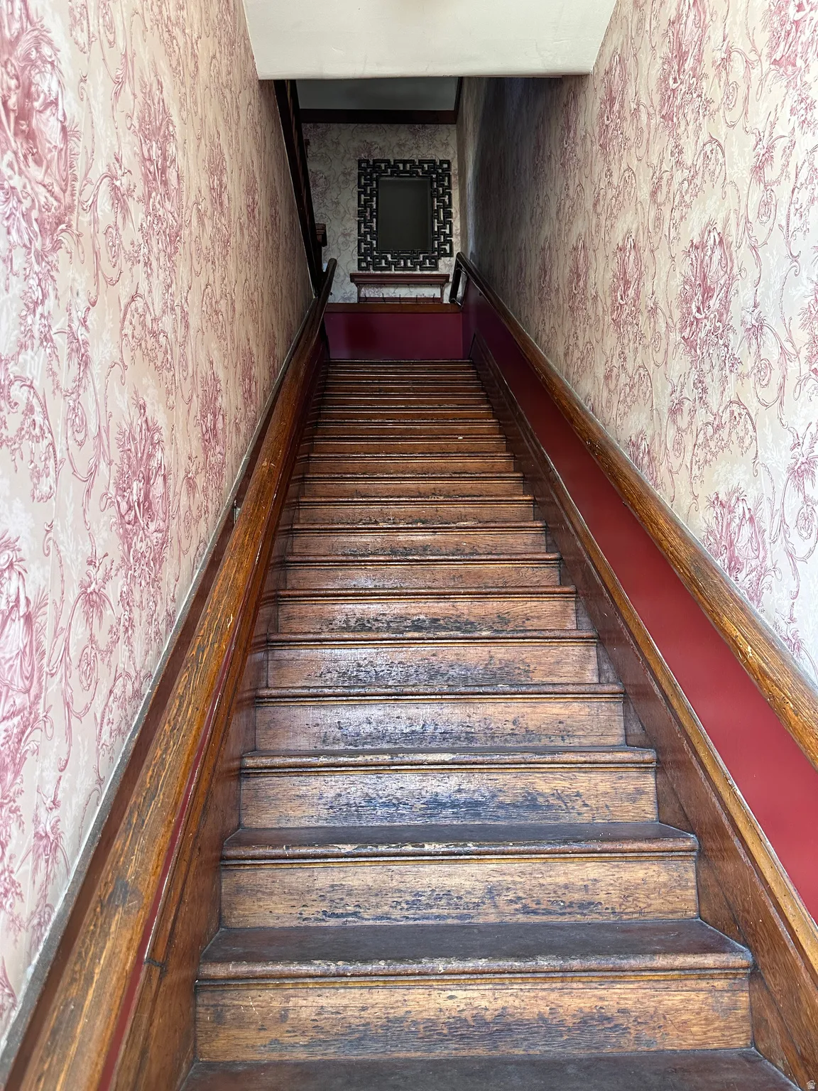 Stairs featuring wallpapered walls and wainscoting