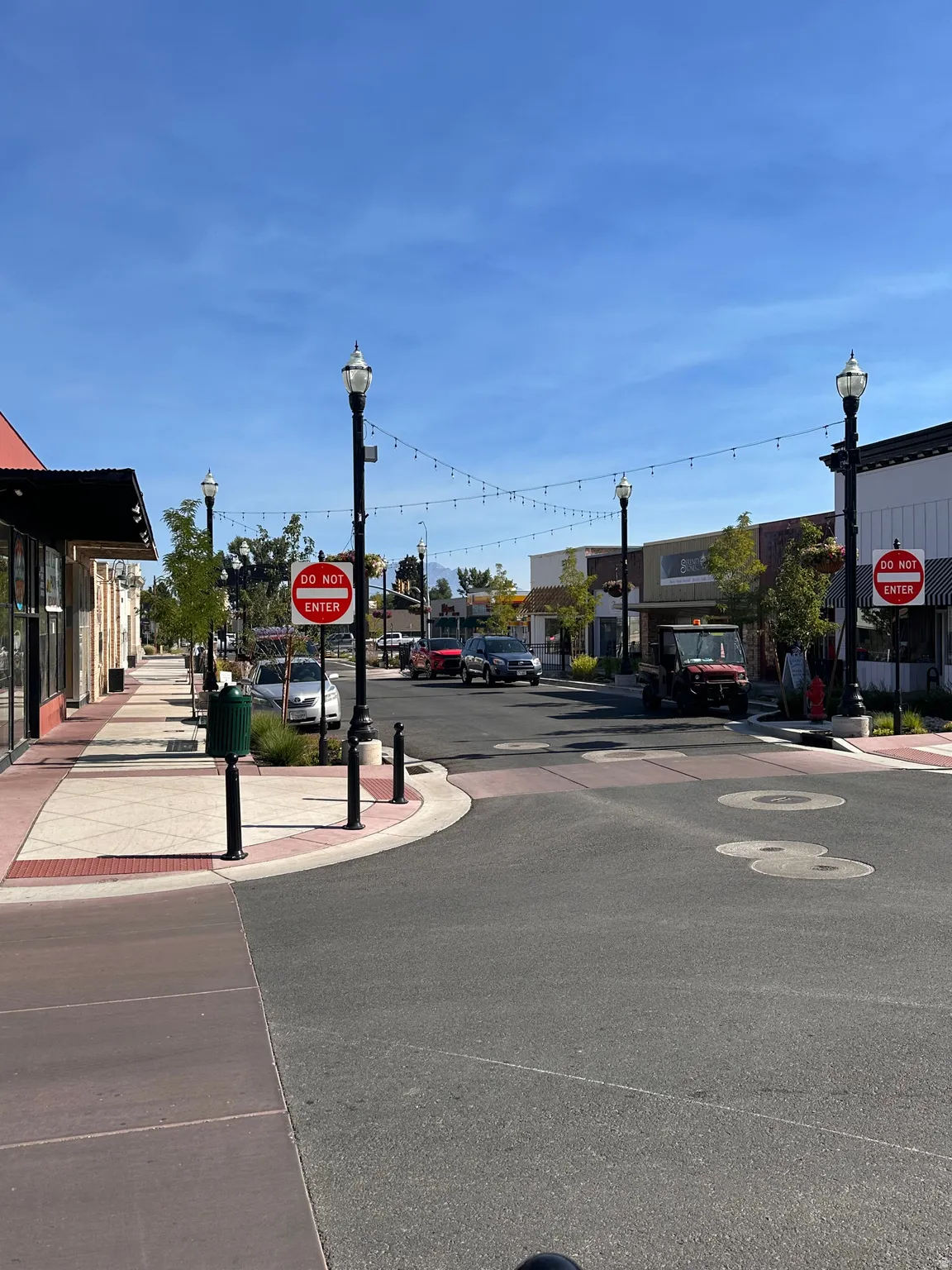 View of asphalt street featuring street lighting, traffic signs, and sidewalks