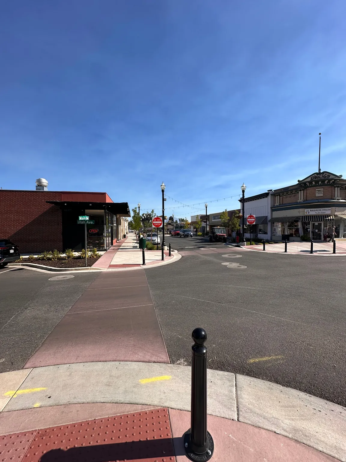 View of asphalt street featuring traffic signs, sidewalks, and curbs