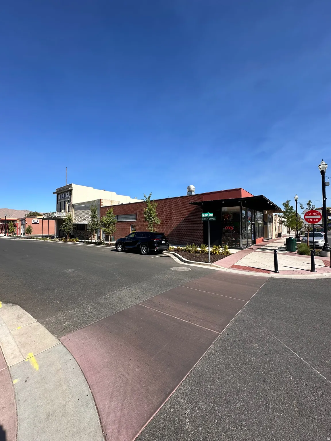 View of asphalt street featuring sidewalks, street lighting, traffic signs, and curbs
