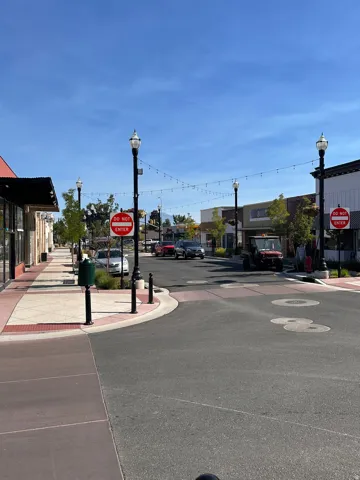 View of asphalt street featuring street lighting, traffic signs, and sidewalks