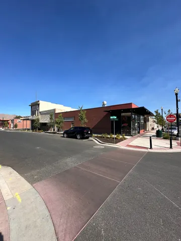 View of asphalt street featuring sidewalks, street lighting, traffic signs, and curbs