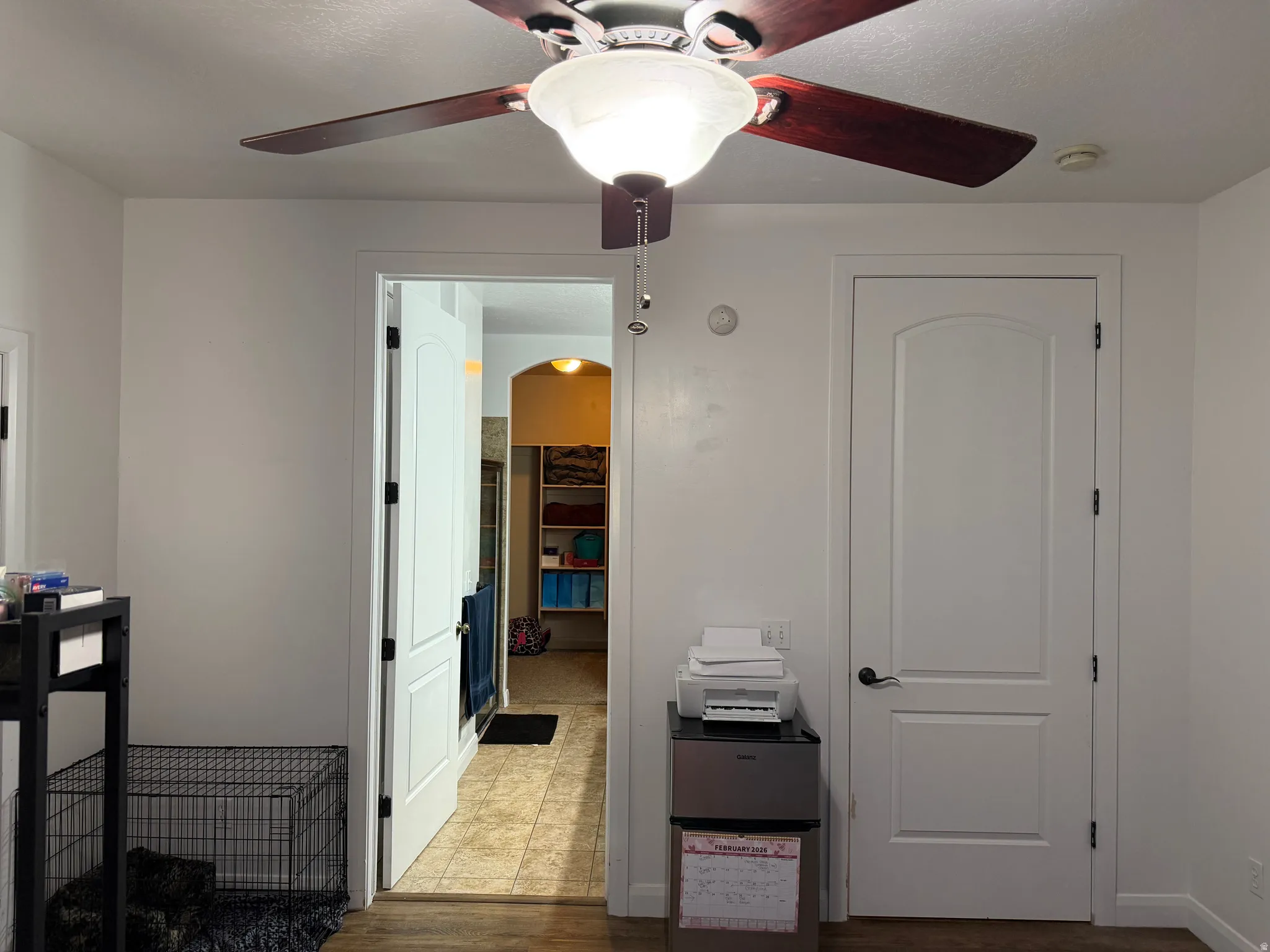 Bedroom with a spacious closet, ceiling fan, arched walkways, and dark wood-type flooring