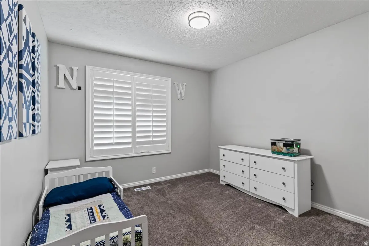 Bedroom featuring a textured ceiling and dark colored carpet