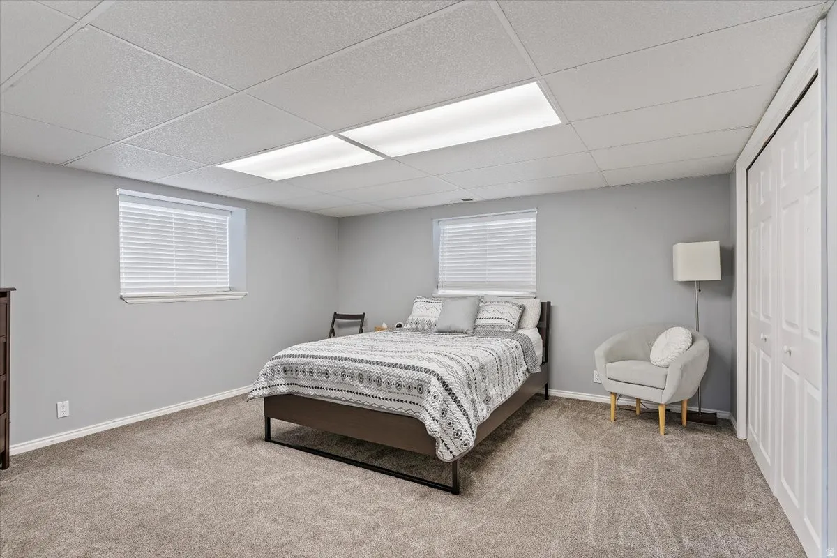 Bedroom with a drop ceiling, light colored carpet, and a closet