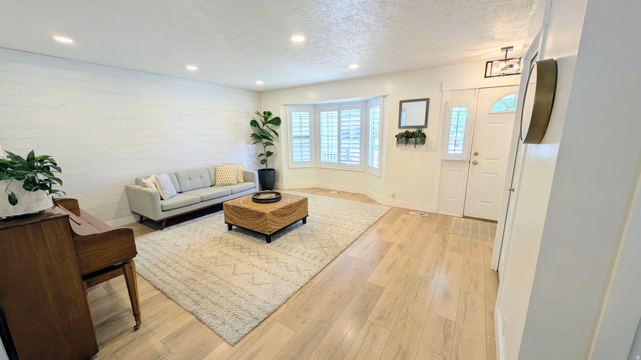 Living area featuring light wood-finish flooring, recessed lighting, and a prominent shiplap accent wall
