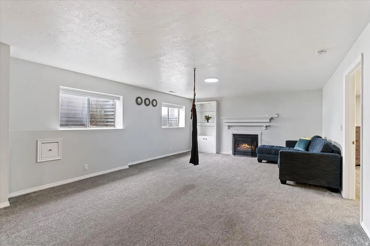 Living area with a lit fireplace, a textured ceiling, and carpet floors