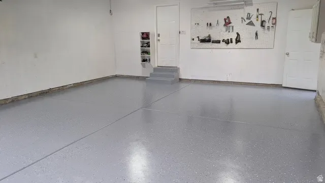 Garage featuring a gray epoxy floor finish, white walls, and built-in steps