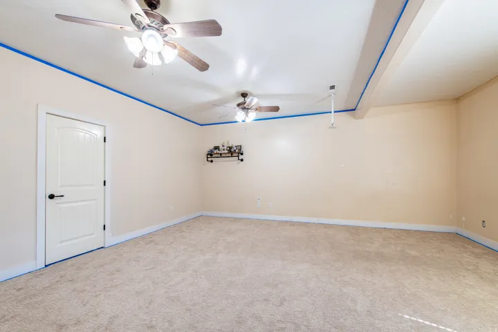 Carpeted empty room with a ceiling fan and baseboards